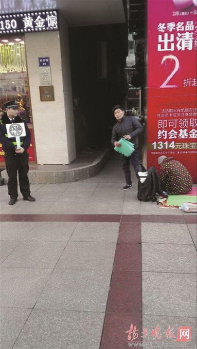 城管在假乞丐旁舉牌 這個“乞丐”很有故事曾去過新加坡乞討